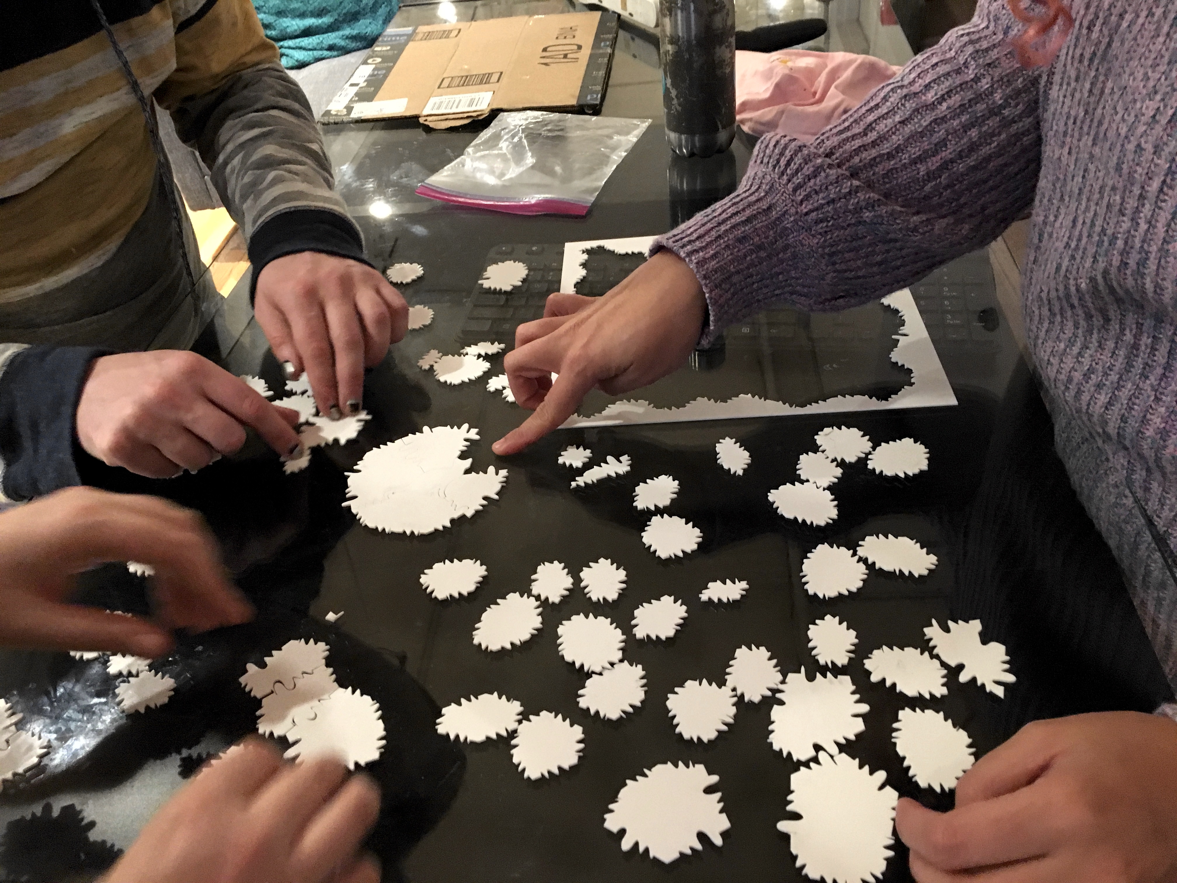 Several people gathered around the puzzle, working on solving it.